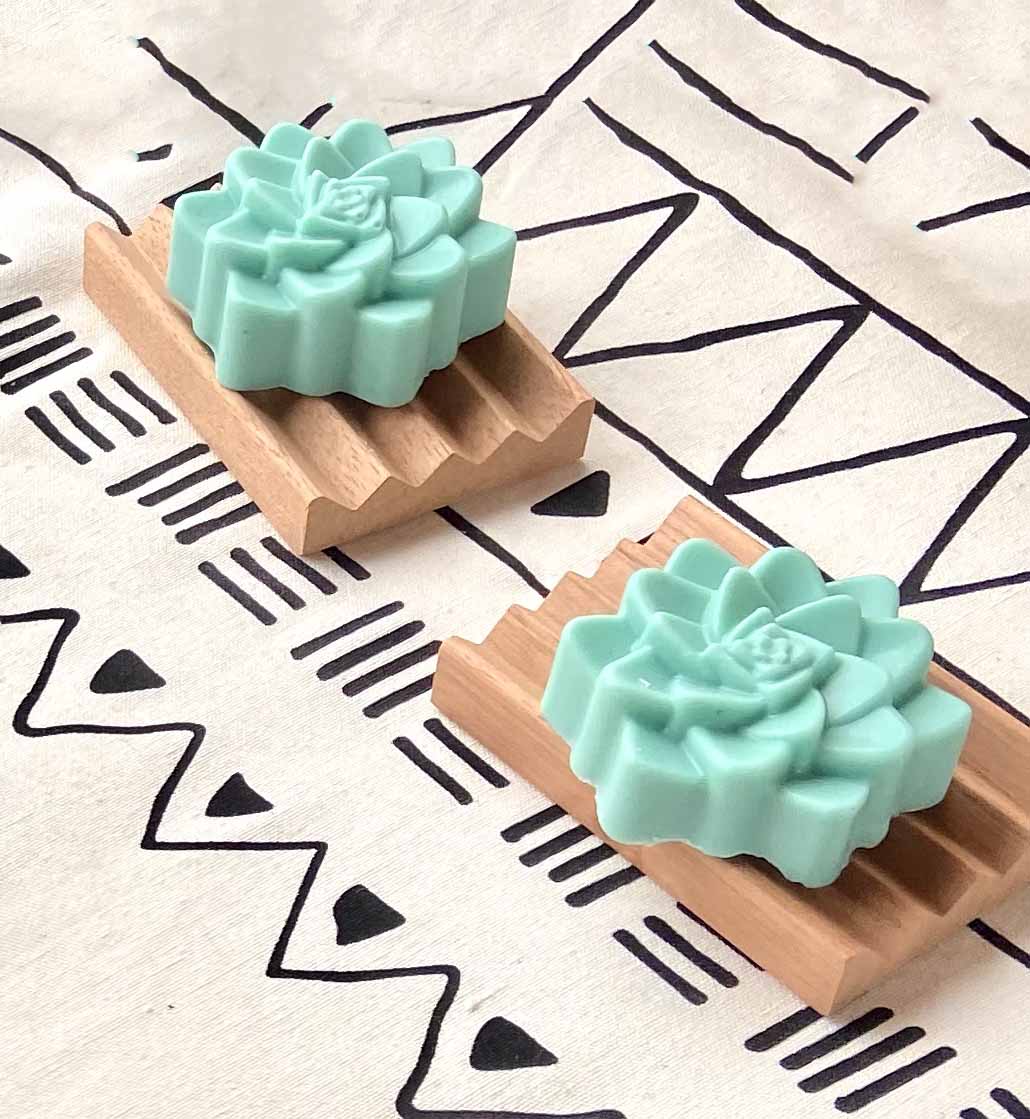 Green flower soaps sitting on wooden dishes