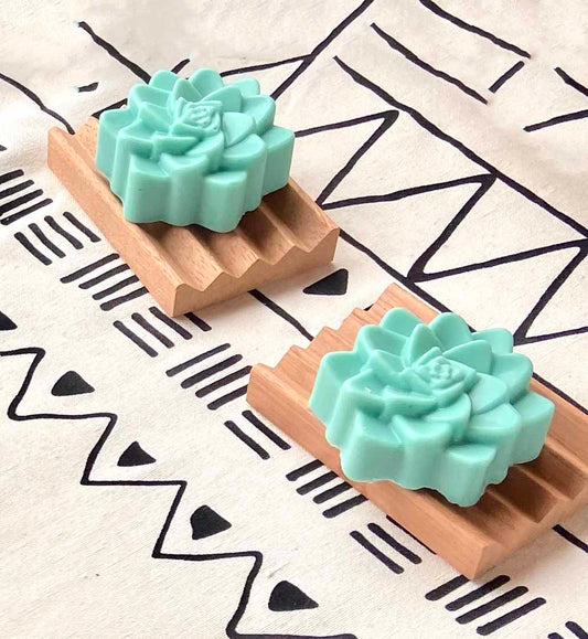 Green flower soaps sitting on wooden dishes